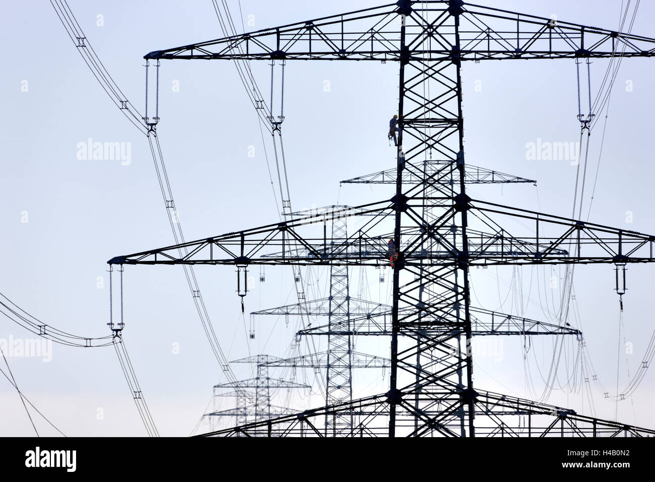 Alta tensione poli, due uomini arrampicata in corrispondenza di un polo, sagome, luce posteriore Foto Stock