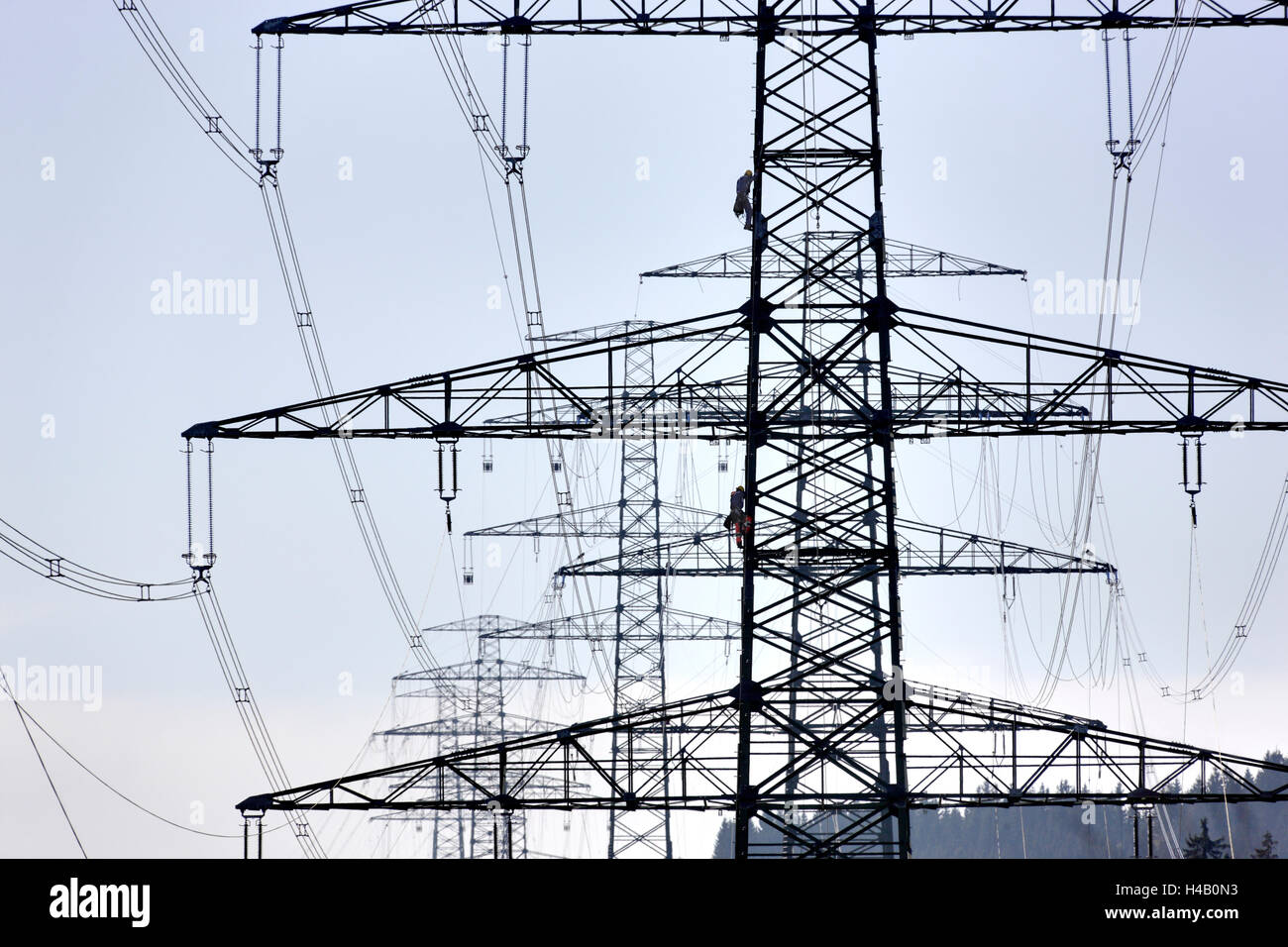 Alta tensione poli, due uomini arrampicata in corrispondenza di un polo, sagome, luce posteriore Foto Stock