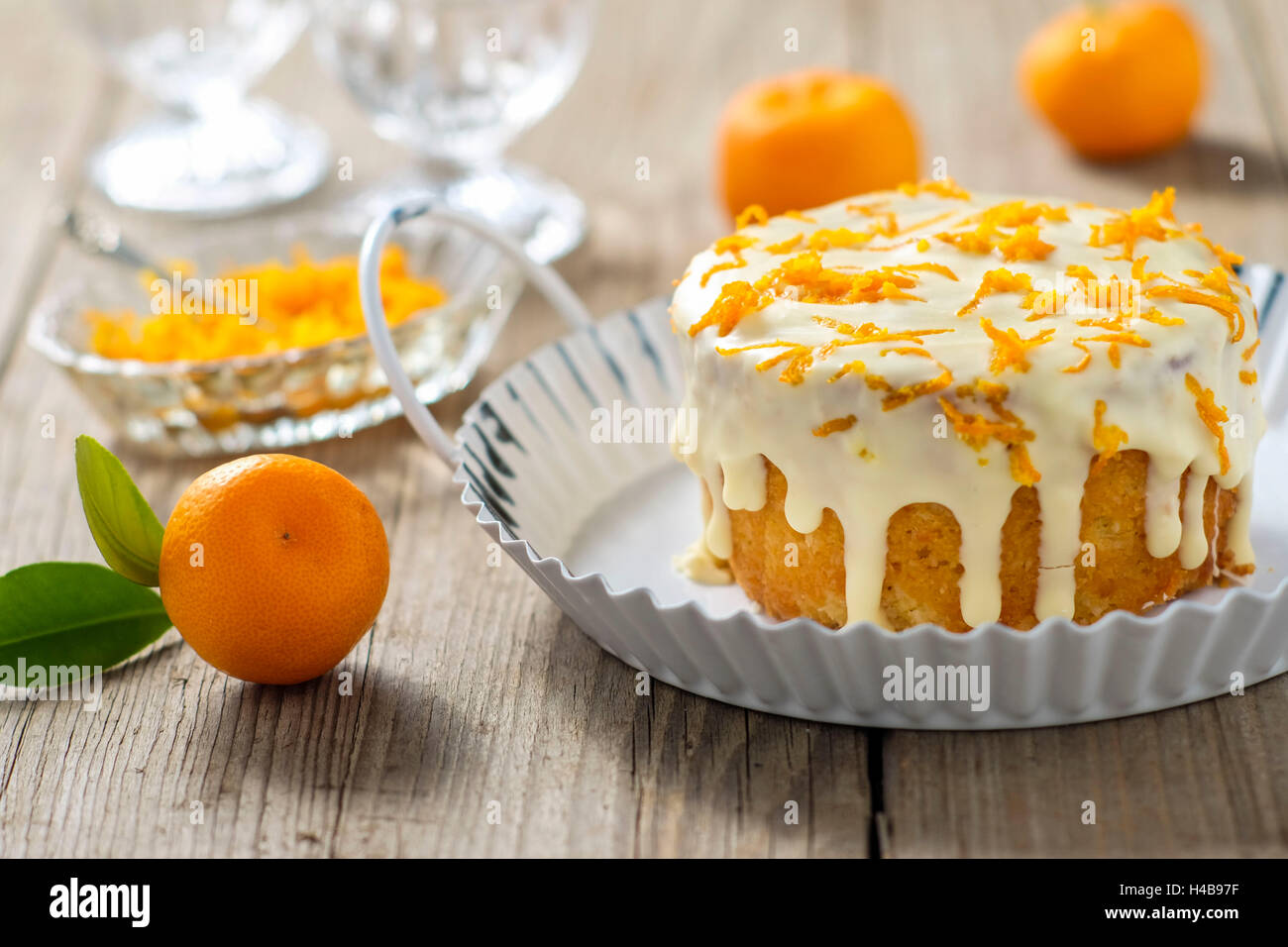 Piccola torta arancione con glassa bianca sul tavolo di legno Foto Stock