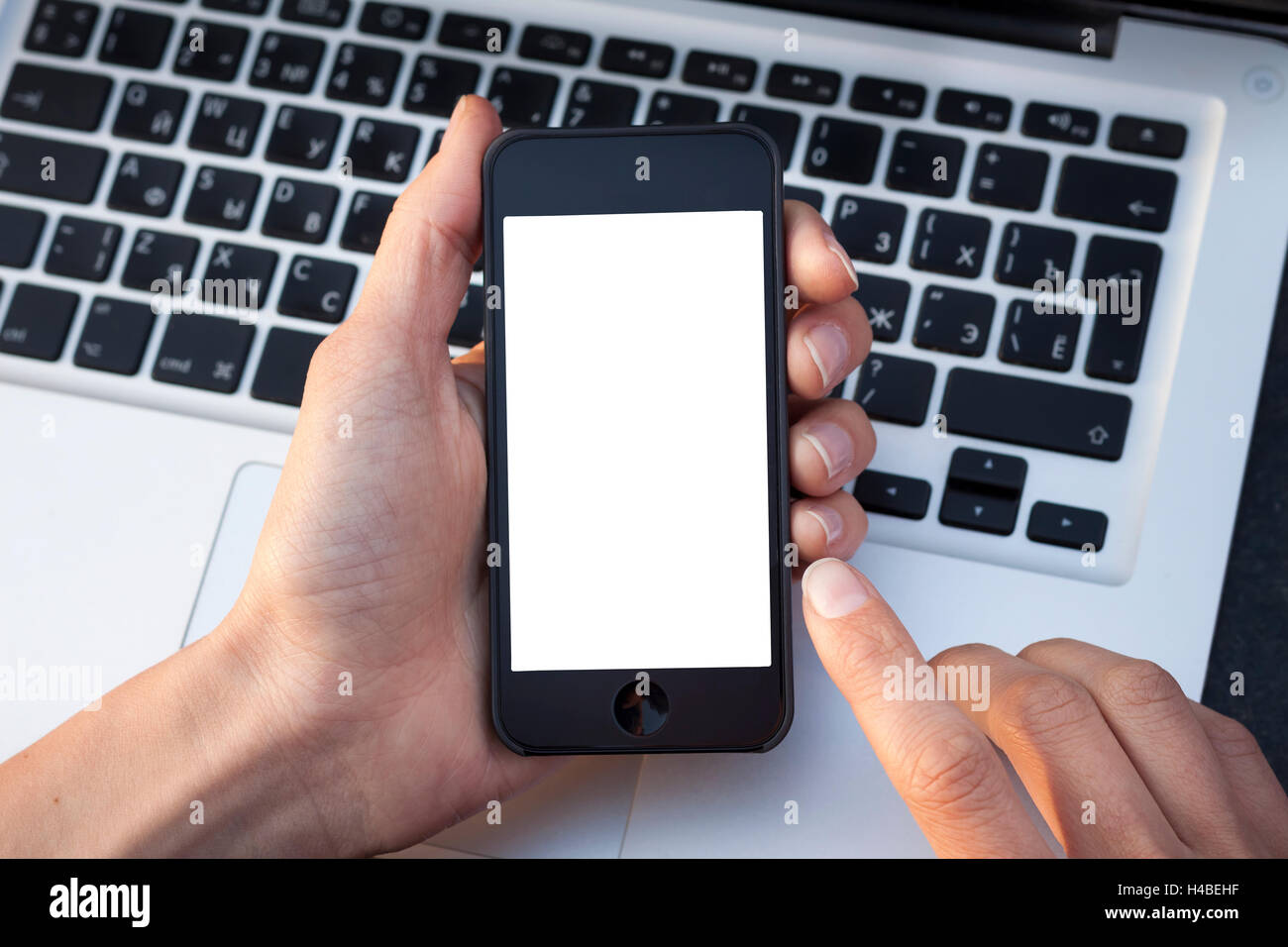 Donna mani dello smartphone mostrando la schermata bianca con la tastiera portatile in background Foto Stock