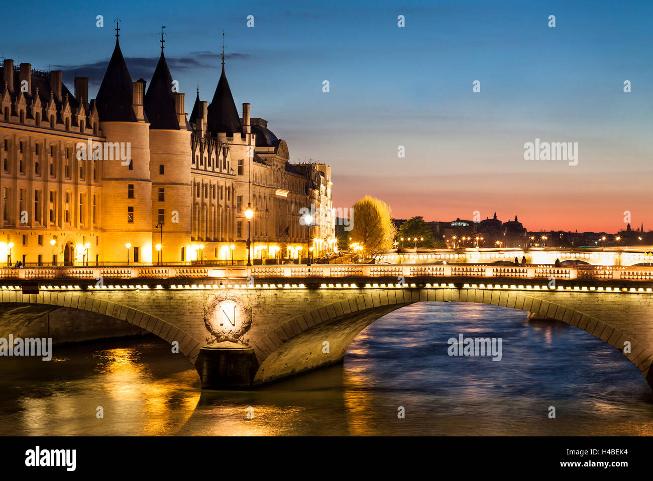 Vista di Parigi di notte con un ponte sopra il fiume Senna e la Conciergerie edificio vicino a Notre Dame Foto Stock