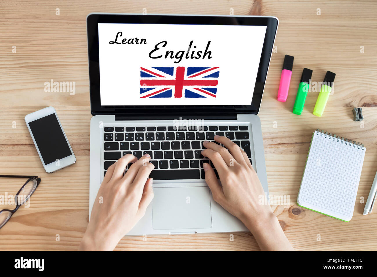 Donna di apprendimento della lingua inglese online con il computer a casa, bandiera britannica in background, top-view Foto Stock