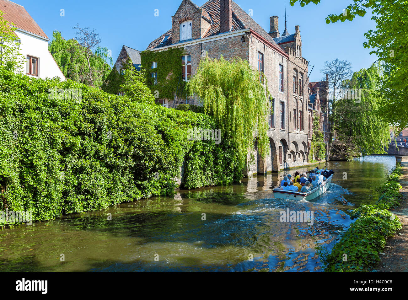 BRUGES, Belgio - Aprile 6, 2008: turisti galleggiare su una barca attraverso il Dijver canale vicino case vintage Foto Stock