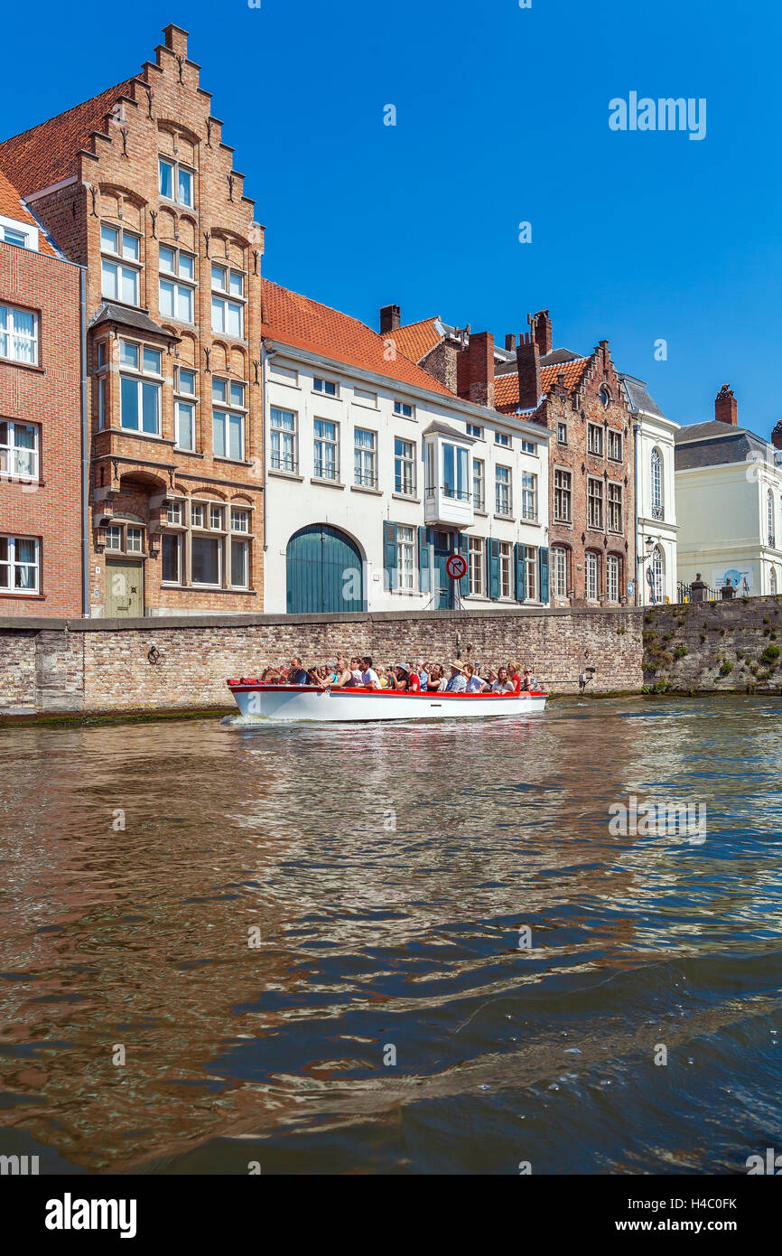 BRUGES, Belgio - Aprile 6, 2008: turisti galleggiare su una barca attraverso il Dijver canale vicino case vintage Foto Stock