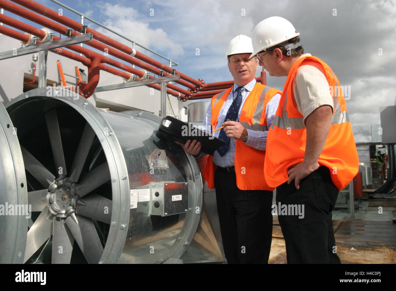 Gli ingegneri edili ispezionare il nuovo impianto di condizionamento sul tetto di un centro di Londra edificio per uffici Foto Stock