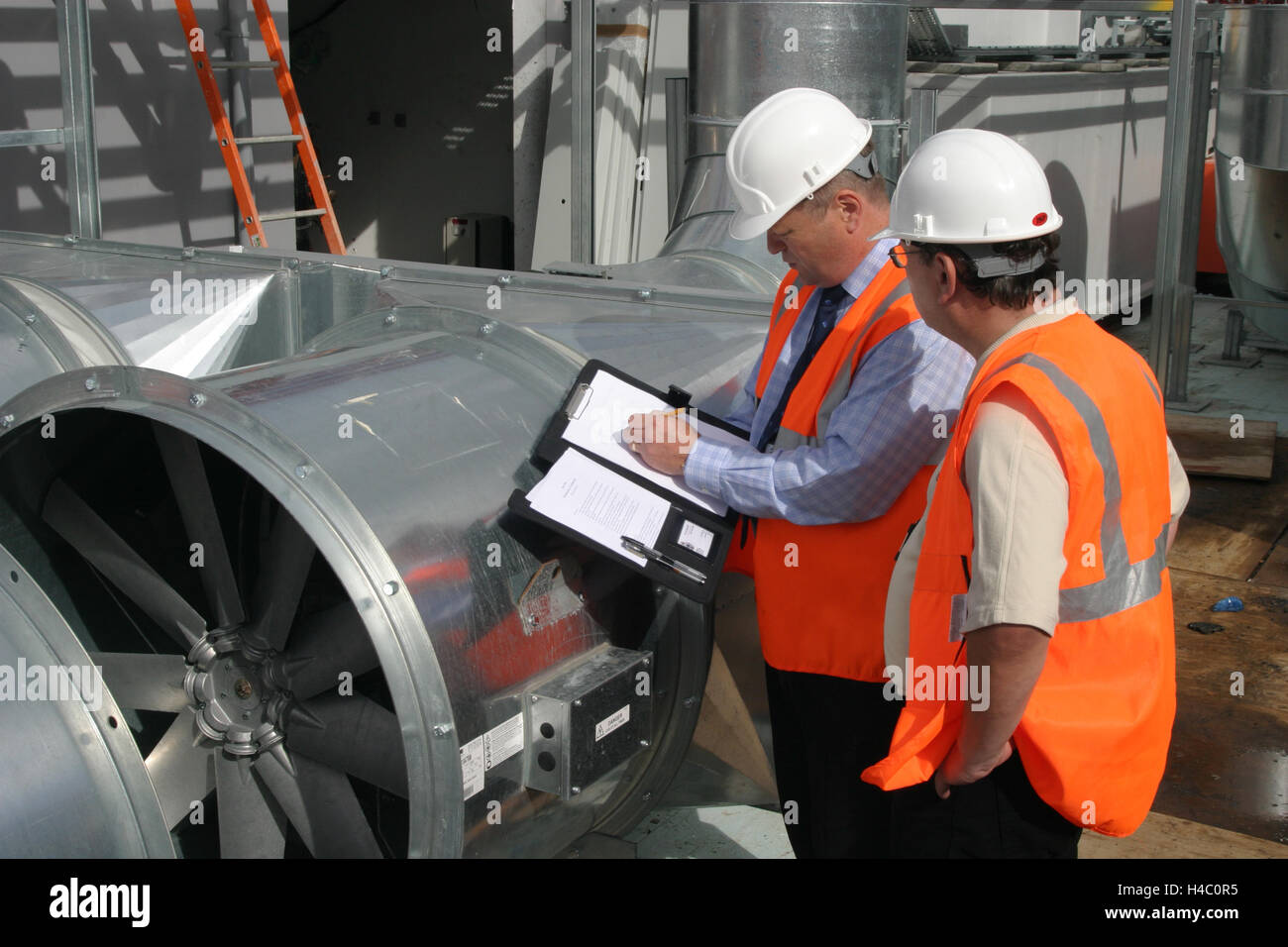 Gli ingegneri edili ispezionare il nuovo impianto di condizionamento sul tetto di un centro di Londra edificio per uffici Foto Stock