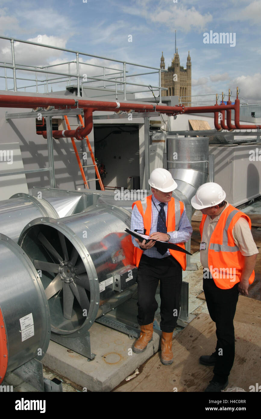 Gli ingegneri edili ispezionare il nuovo impianto di condizionamento sul tetto di un centro di Londra edificio per uffici Foto Stock