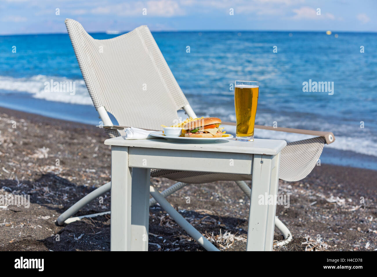 Patatine fritte e un panino sulla spiaggia Foto Stock