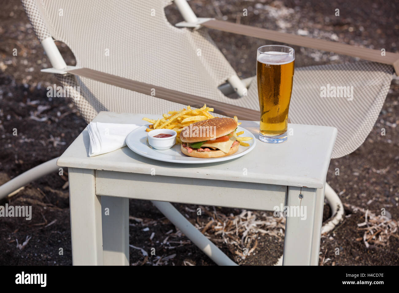 Patatine fritte e un panino sulla spiaggia Foto Stock