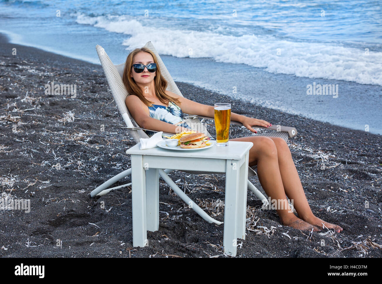 Giovane donna sulla spiaggia e fast food sul tavolo Foto Stock