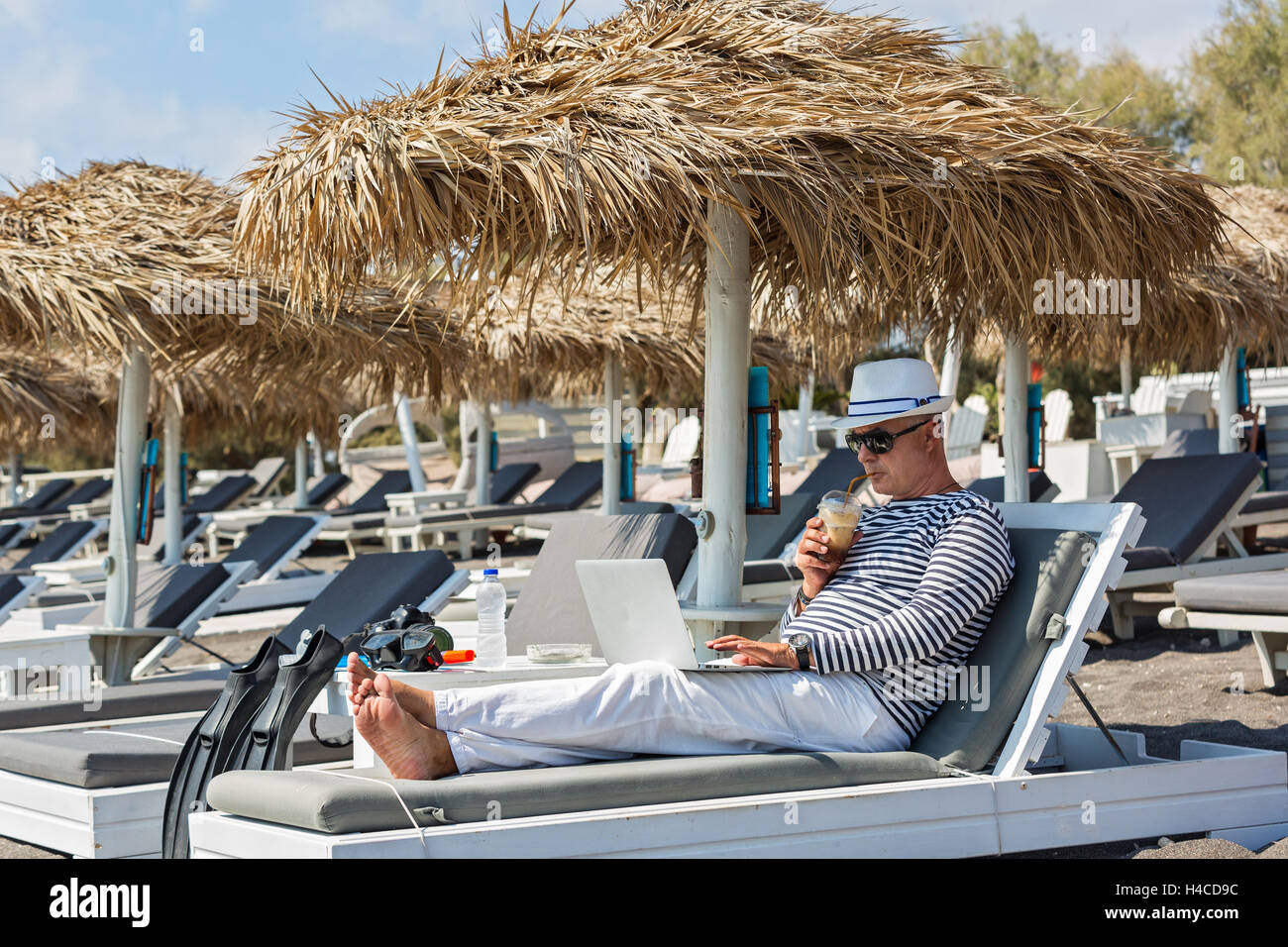Uomo che lavora al computer sdraiato sulla spiaggia Foto Stock
