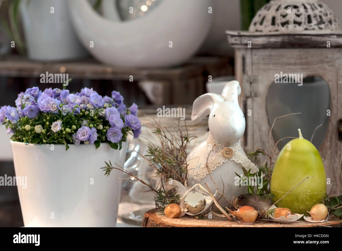 Decorazione di pasqua nel negozio di fiori. Vaso con mauve campanule, una lanterna  di vecchi dalle intemperie in legno. In primo piano di terracotta piccoli  coniglietto di Pasqua, verde uovo di pasqua