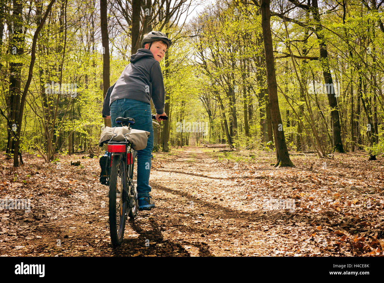 Ragazzo presso la scuola di massa vecchia persona va con il suo radian da una molla in legno, oltre, guarda indietro per la fotocamera Foto Stock