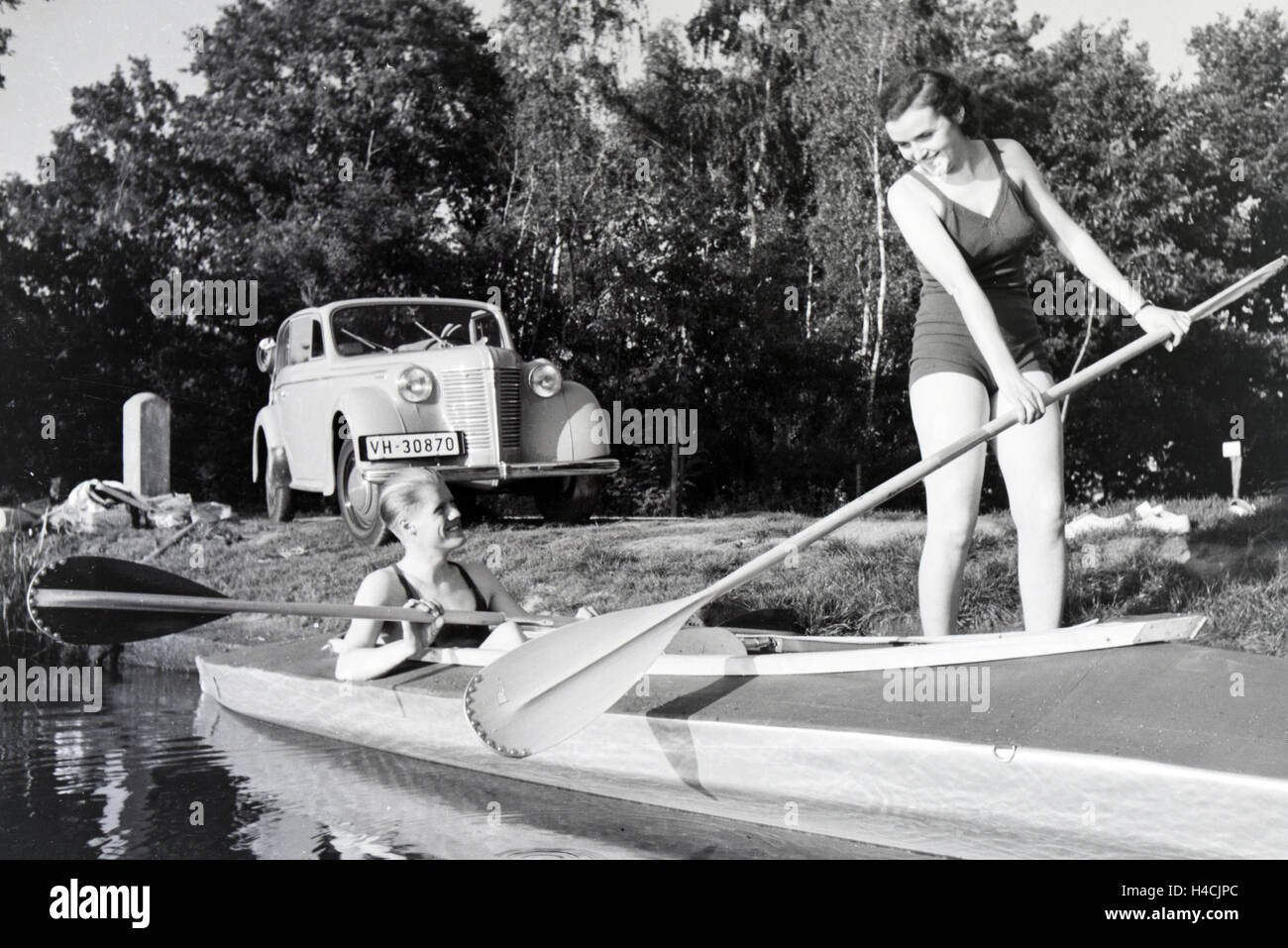 Junges Paar paddelt im Boot in Nhe des Ufers auf einem vedere, Deutschland 1930er Jahre. Coppia giovane paddling in una barca sul lago vicino al fiume, Germania 1930 Foto Stock