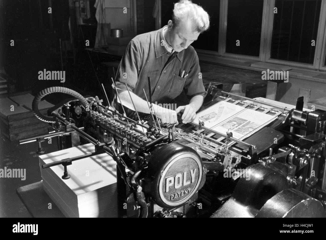 Ein Drucker bei der Arbeit an der M.A.N. Maschine "Poly brevetto", Deutsches Reich 1930er Jahre. Una stampante funzionante con la macchina M.A.N. "Poly brevetto", Germania 1930 Foto Stock