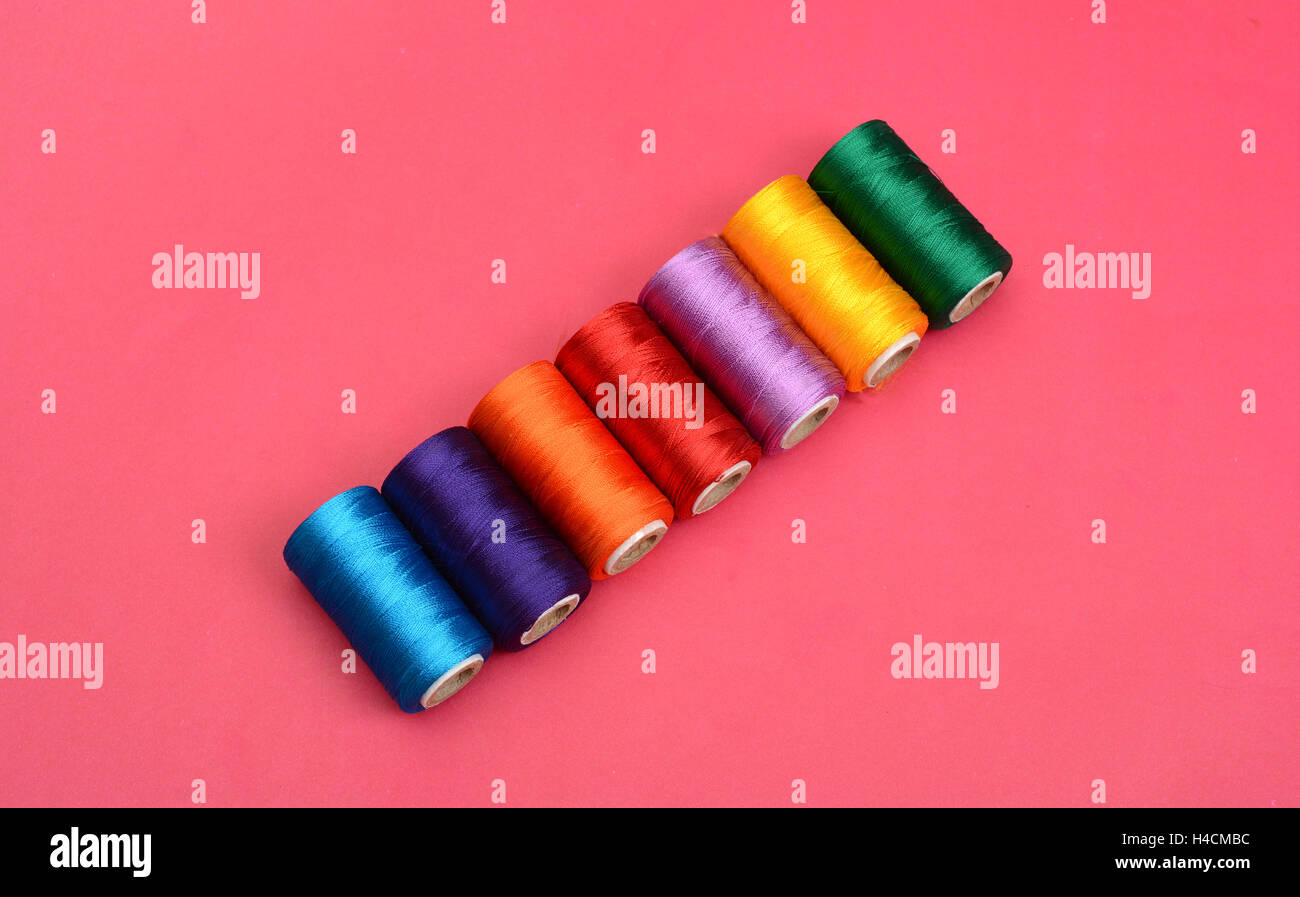 Bobine di coloratissimi fili di seta su sfondo rosa. Foto Stock