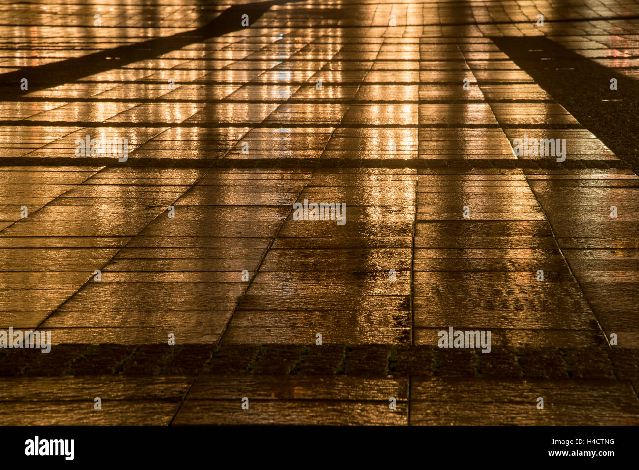 Golden illuminato quadrato nella città dalle luci riflessione in corrispondenza di una notte piovosa Foto Stock