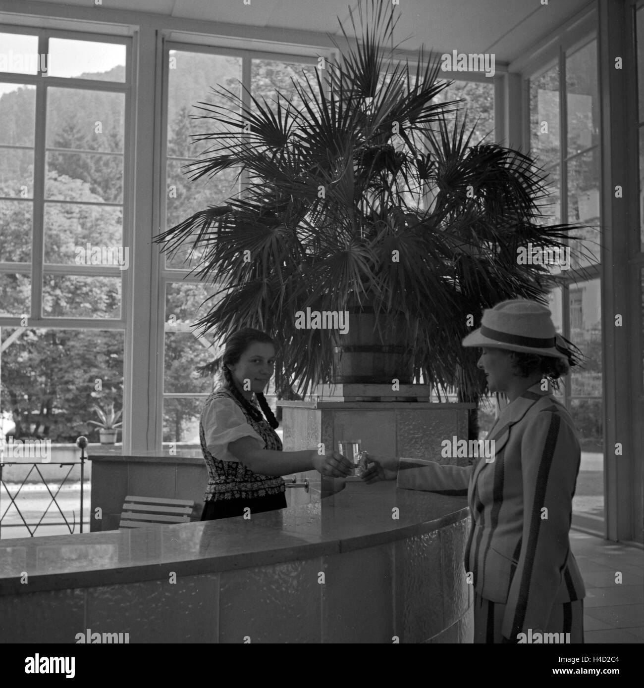 Eine Frau als Gast an der Rezeption eines Kurhotels in Wildbad im Schwarzwald, Deutschland 1930er Jahre. Ospiti di sesso femminile presso la reception della spa resort hotel a Wildbad nella Foresta Nera, Germania 1930s. Foto Stock