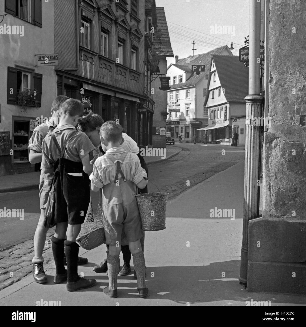 Vier Jungen in der Straße vor dem Kürschnerbetrieb Karl Rometsch und dem Köhle Gemüsehaus in Wildbad im Schwarzwald, Deutschland 1930er Jahre. Quattro ragazzi al via davanti a Karl Rometsch pellicciaio del workshop e del Koehle greengrocery shop presso la città di Wildbad nella Foresta Nera, Germania 1930s. Foto Stock