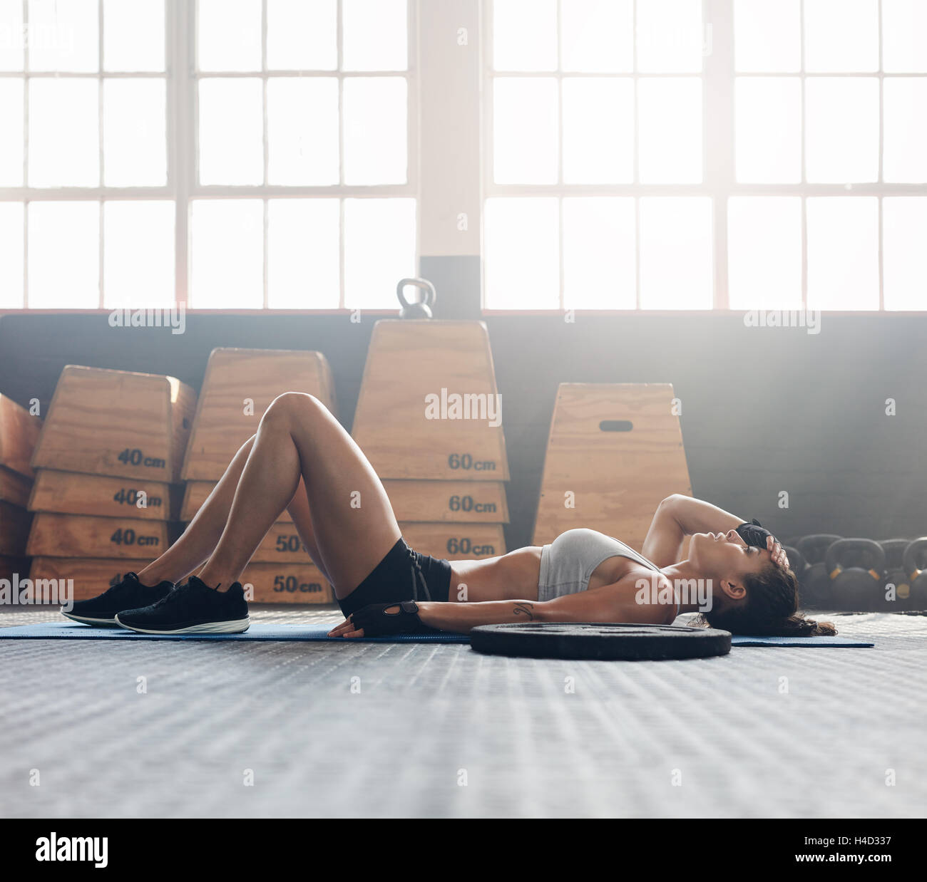 Giovane donna sdraiata sulla schiena in palestra dopo il suo allenamento. Donna fitness relax dopo la sessione di allenamento. Foto Stock