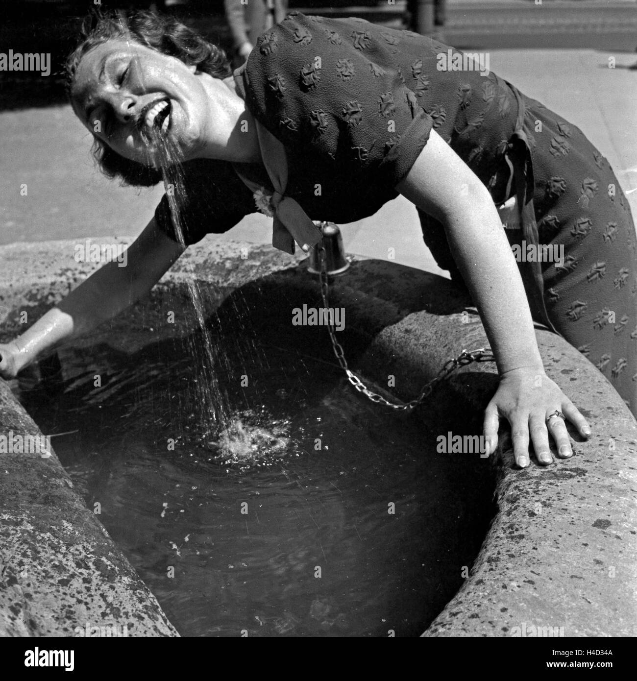 Eine Frau trinkt Wasser aus einem Springbrunnen in der Innenstadt von Stuttgart, Deutschland 1930er Jahre. Una donna di bere acqua da una fontana presso la vecchia città di Stoccarda, Germania 1930s. Foto Stock