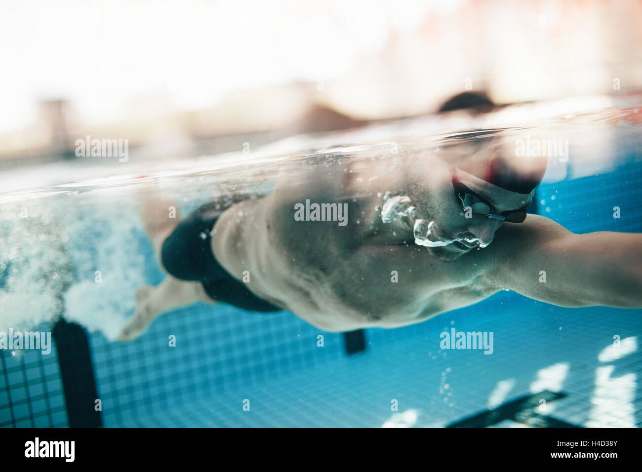 Riprese subacquee di atleta maschio di nuoto in piscina. Giovane uomo nuotare il crawl anteriore in una piscina. Foto Stock