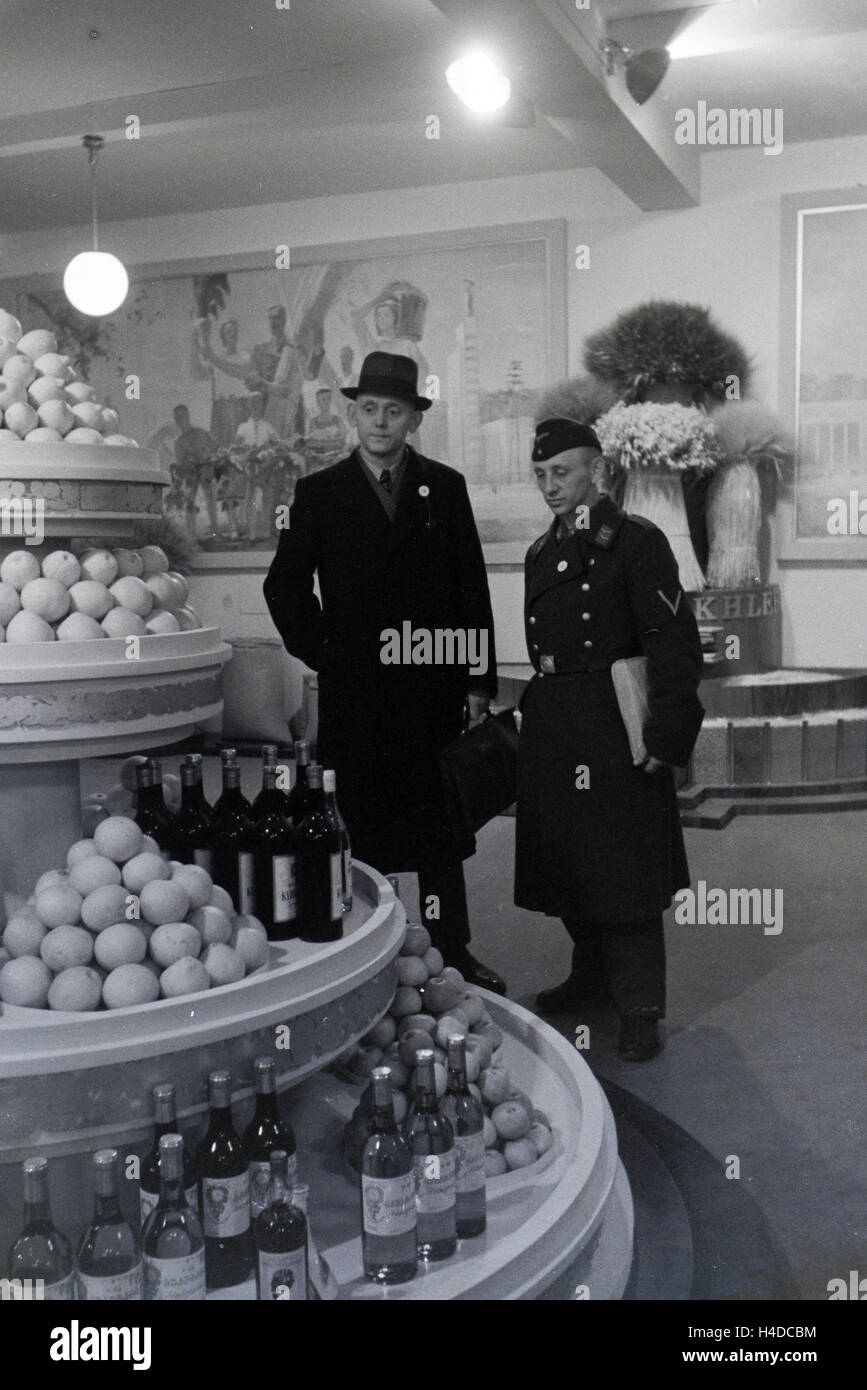 Besucher der Leipziger Frühjahrsmesse vor einem Messestand mit Spezialitäten südländischen, Deutschland 1941. I visitatori della Leipziger Frühjahrsmesse nella parte anteriore del piedistallo con delicatezza del Mediterraneo, Germania 1941. Foto Stock