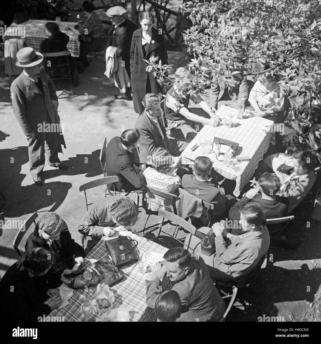 Menschen sitzen in einem Gartenrestaurant (ristorante nel giardino), Deutschland 1930er Jahre. La gente seduta in un ristorante con giardino, Germania 1930s. Foto Stock