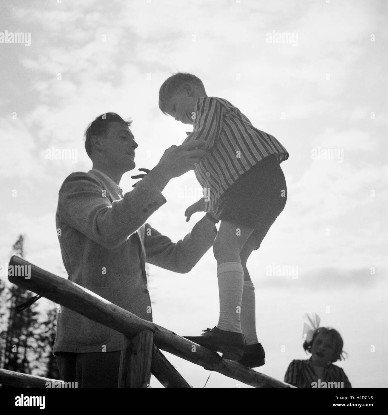 Ein Mann hält einen kleinen Jungen, der auf einem Geländer balanciert, Deutschland 1930er Jahre. Un uomo in possesso di un ragazzino che è in equilibrio su una ringhiera, Germania 1930s. Foto Stock