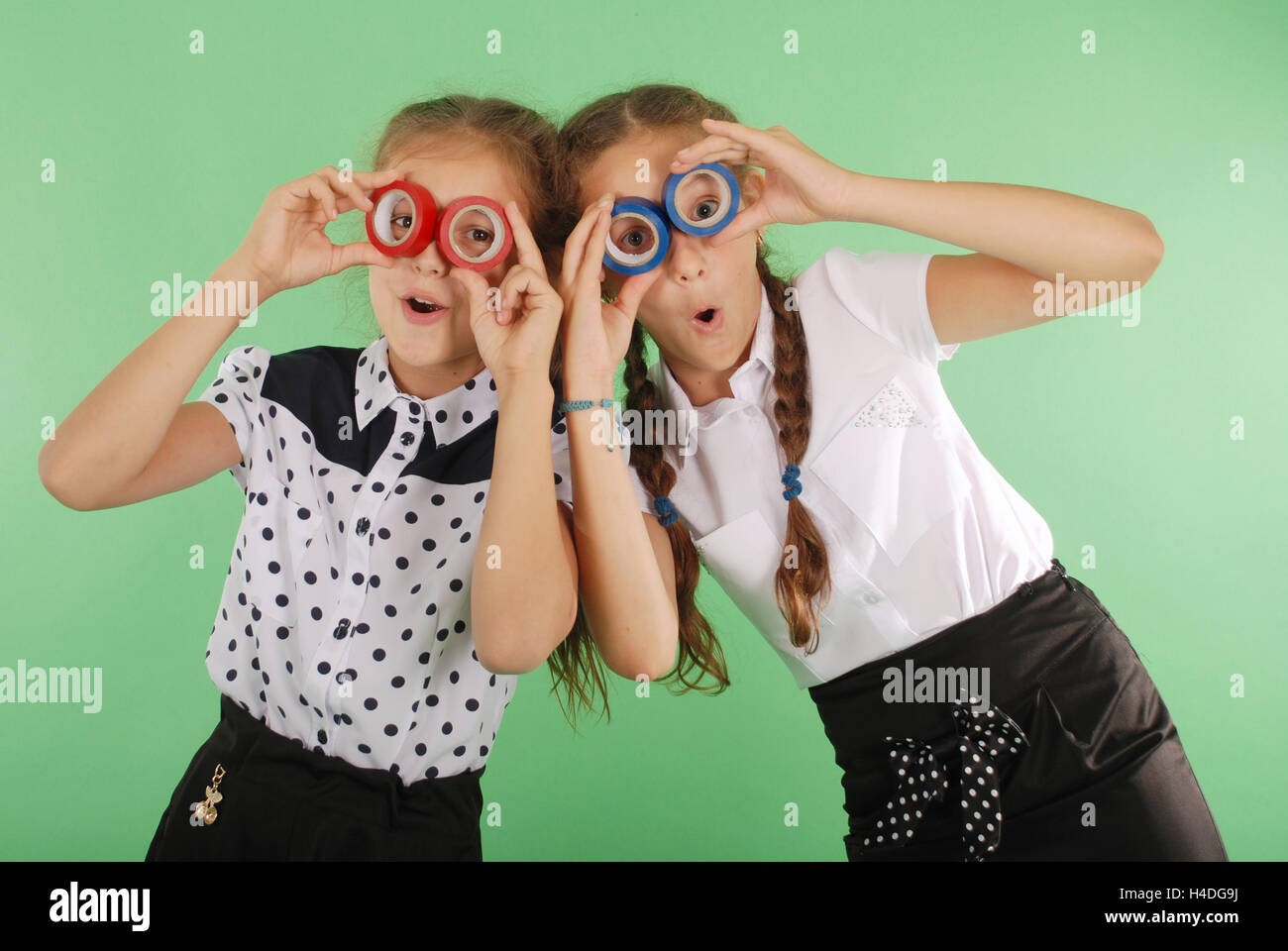 Due belle scuola ragazza con due nastri isolanti sugli occhi per guardare radiante su verde Foto Stock