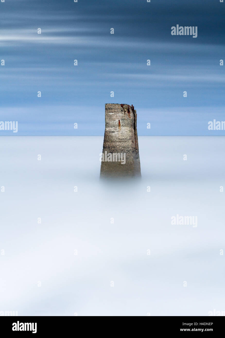 Telemetro colonna di calcestruzzo emergente da una lunga esposizione misty mare come un oceano di cloud computing con la moody blue sky Foto Stock