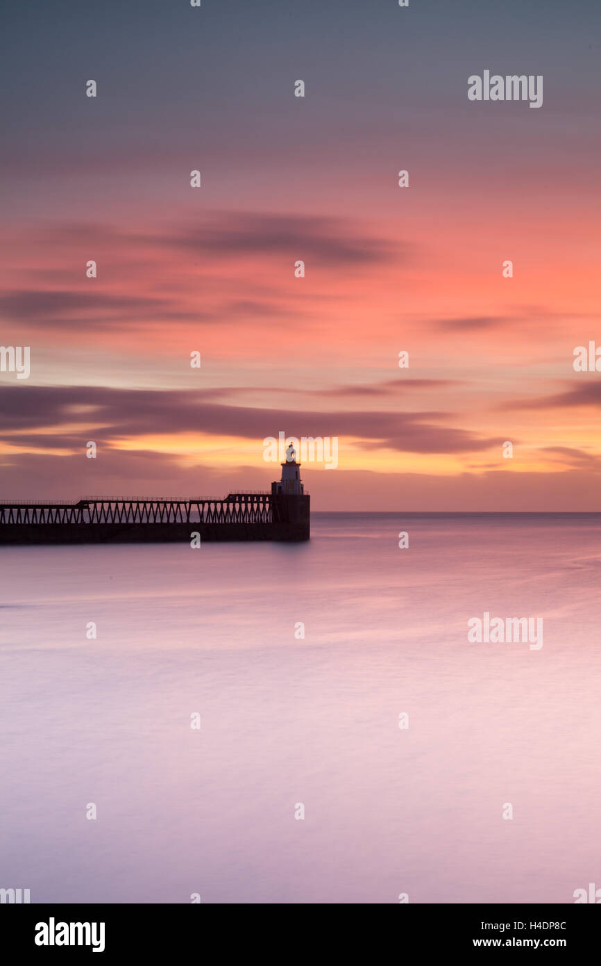 Un colorato di rosa e viola sunrise al piccolo faro di Blyth Porto sulla costa di Northumberland Foto Stock