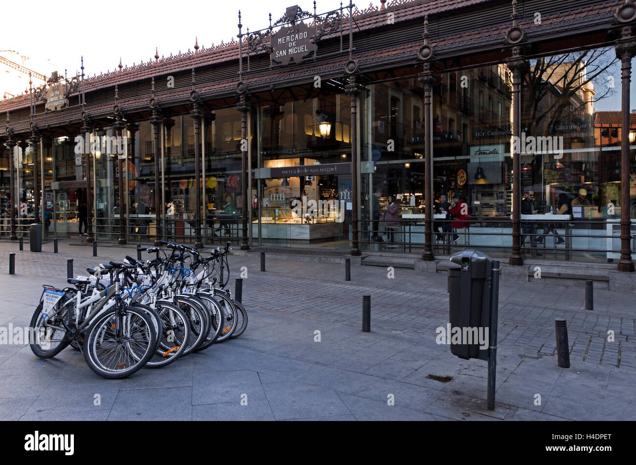 Il Mercado de San Miguel esterno, botique tapas bar e panificio, persone mangiare a contatori all'interno. 8 noleggio moto parcheggiata di fronte. Foto Stock