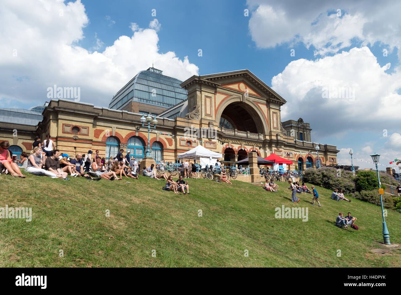 La gente seduta su erba fuori Alexandra Palace durante Alexandra Park Festival, Haringey, London, England, Regno Unito Foto Stock