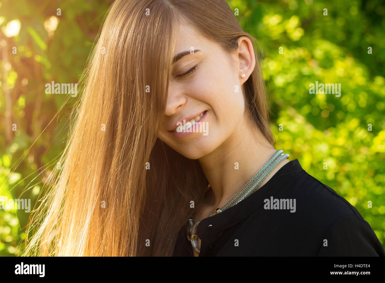 Giovane donna di chiudere gli occhi sullo sfondo di alberi Foto Stock