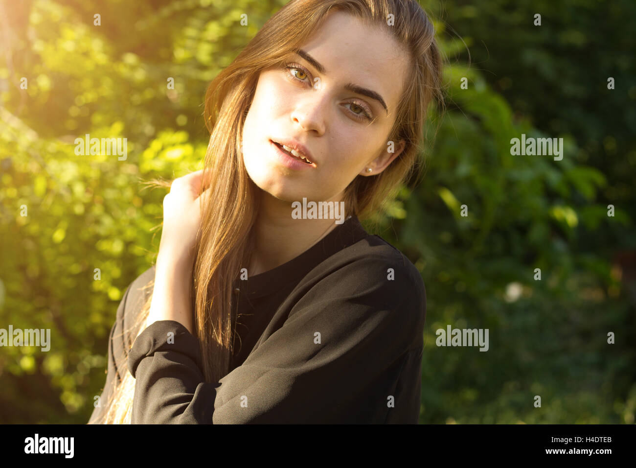 Giovane donna sullo sfondo di alberi e la luce del sole Foto Stock