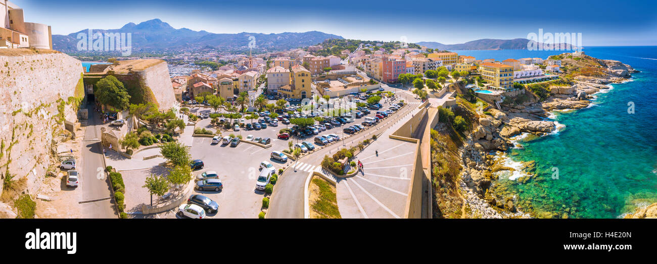 Corsica Costa e case storiche in Calvi città vecchia con il turchese chiaro l'acqua di mare Foto Stock