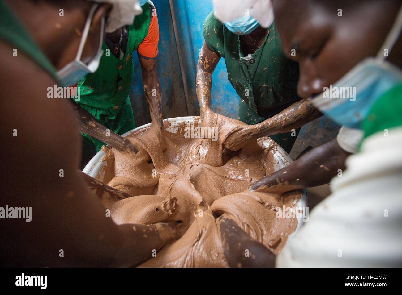 Il lavoro dei dipendenti di varianza manualmente il burro di karité a un commercio equo impianto di produzione in Réo, Burkina Faso. Foto Stock