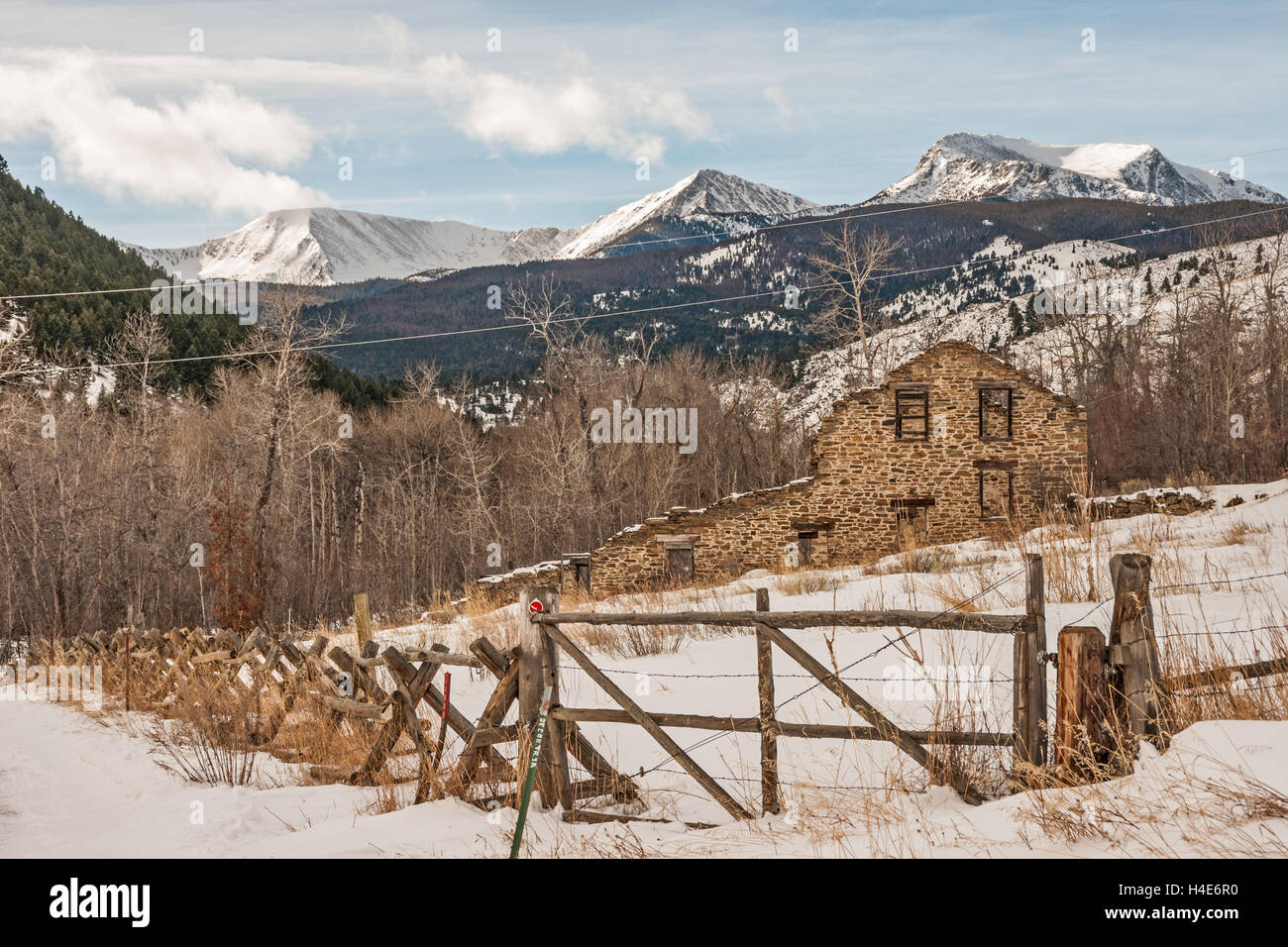 Resti di un venti-stamp gold mulino costruito nel 1883 in Montana su una giornata invernale con la radice del tabacco montagne sullo sfondo Foto Stock