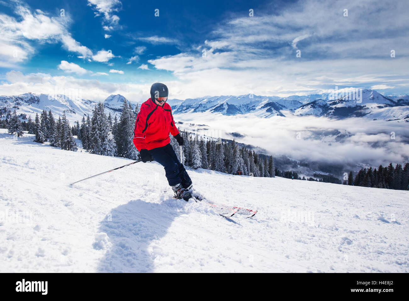 Giovane uomo felice sciare in Kitzbuehel ski resort e godersi il bel tempo con cielo blu e montagne Alpine in Austria Foto Stock