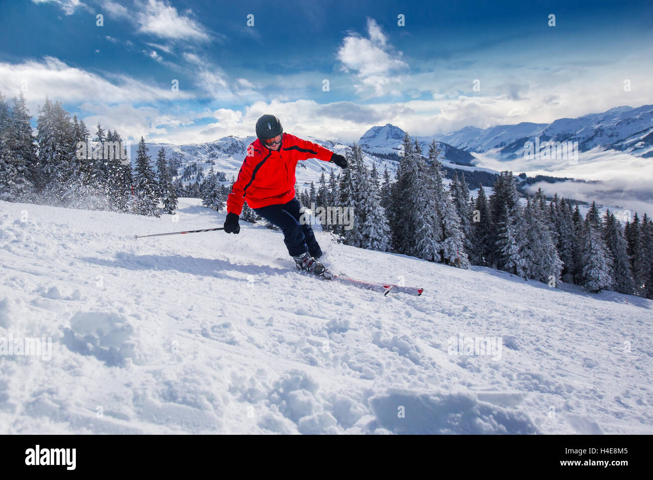 Giovane uomo felice sciare in Kitzbuehel ski resort e godersi il bel tempo con cielo blu e montagne Alpine in Austria Foto Stock