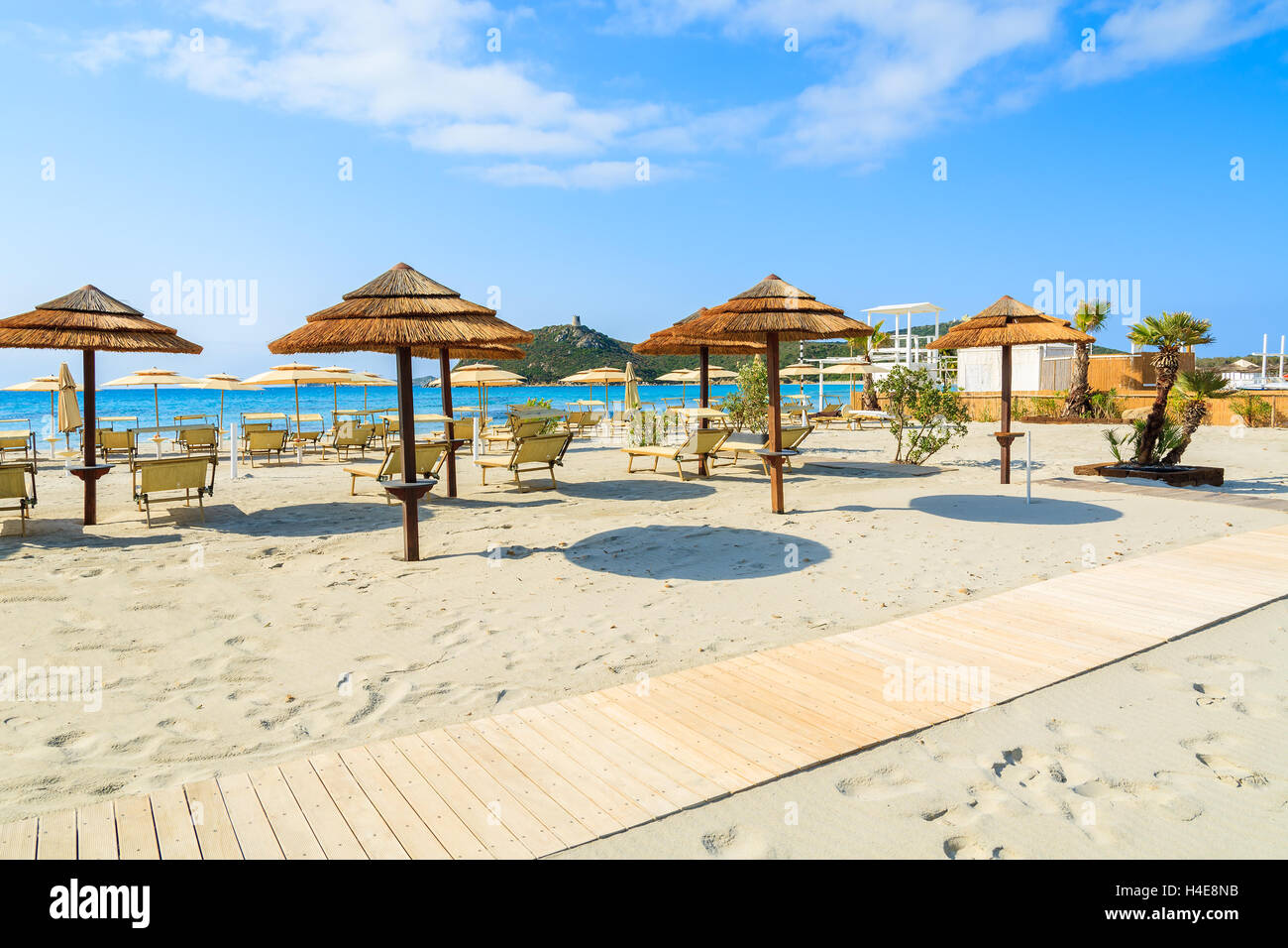 Passerella in legno sul Porto Giunco spiaggia con ombrelloni e sedie, Villasimius, l'isola di Sardegna, Italia Foto Stock