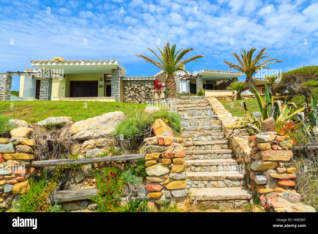 Passerella di pietra a casa per le vacanze sulla costa dell'isola Sardegna vista dal sentiero costiero, Italia Foto Stock