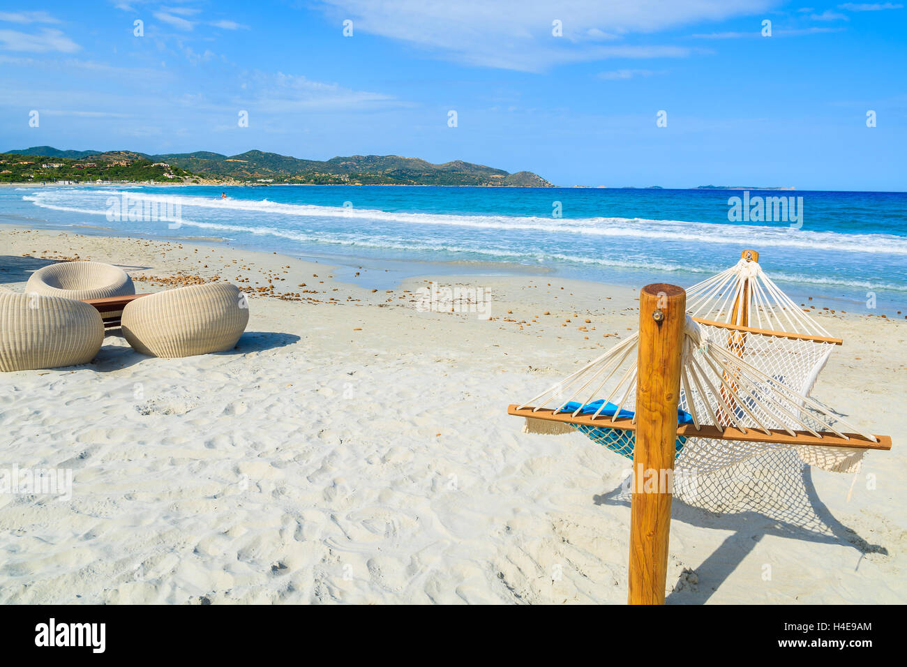 Amaca e sedie a sdraio sulla spiaggia di sabbia bianca di Porto Giunco Bay, l'isola di Sardegna, Italia Foto Stock