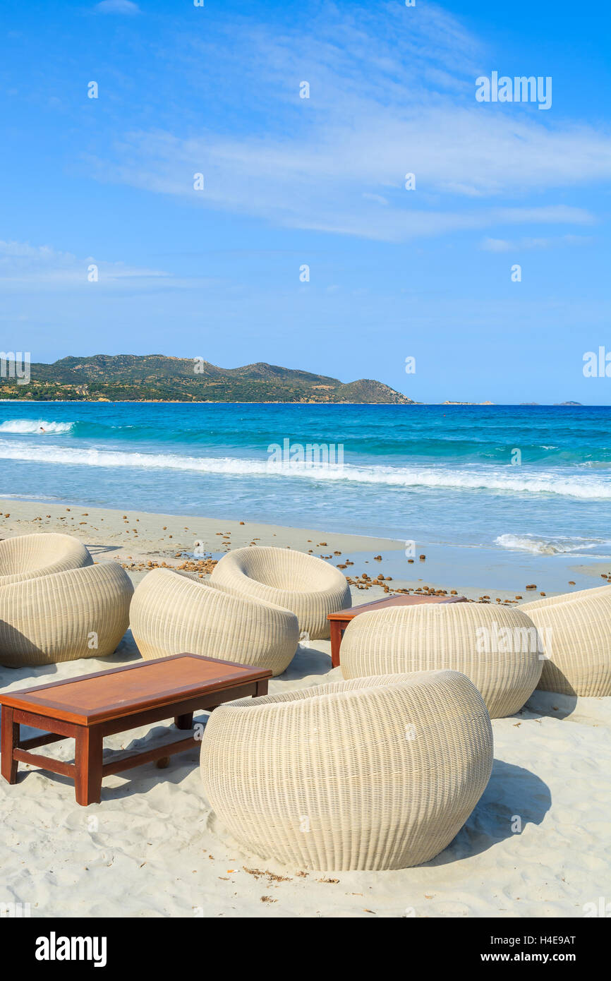 Sedie in un bar sulla spiaggia con un tavolo di legno sulla sabbia bianca di Porto Giunco Bay, l'isola di Sardegna, Italia Foto Stock