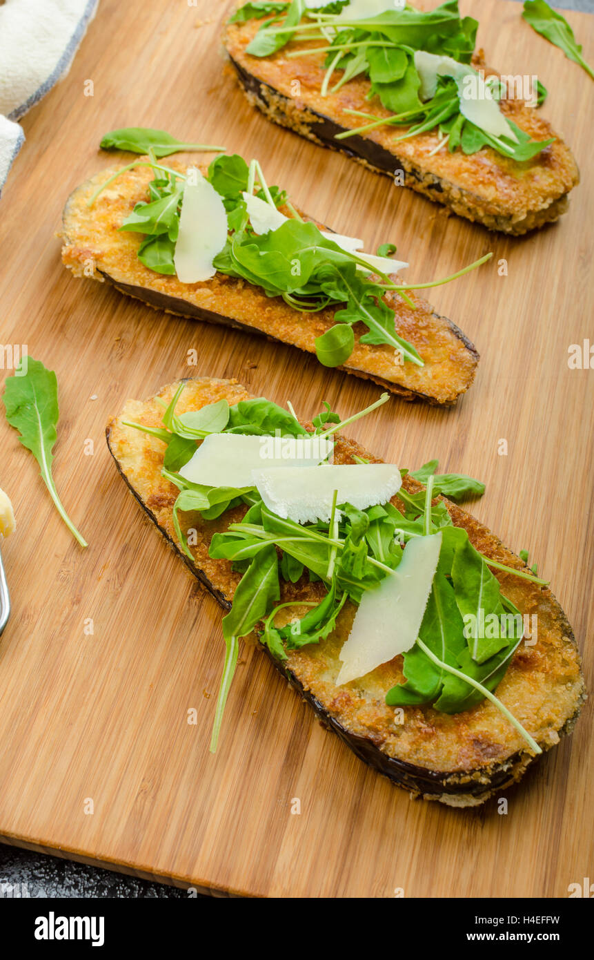 Melanzane fritte, fritto in crosta di parmigiano e insalata di rucola con scaglie di parmigiano, pane fresco - dalamánek ceca Foto Stock