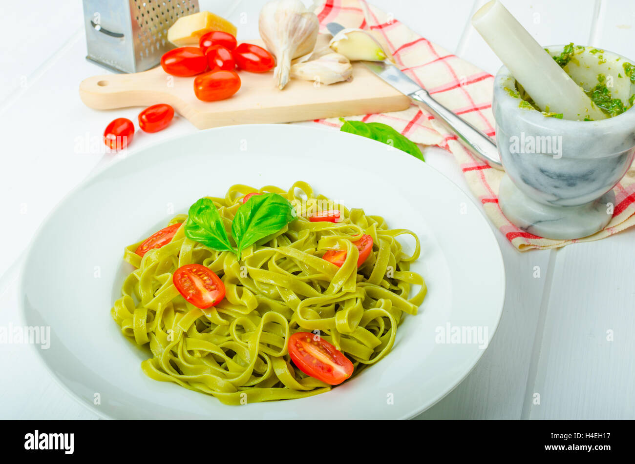 Gli spinaci tagliatelle al pesto di basilico e mini pomodori, wood board, tovaglioli e pesto mortaio Foto Stock