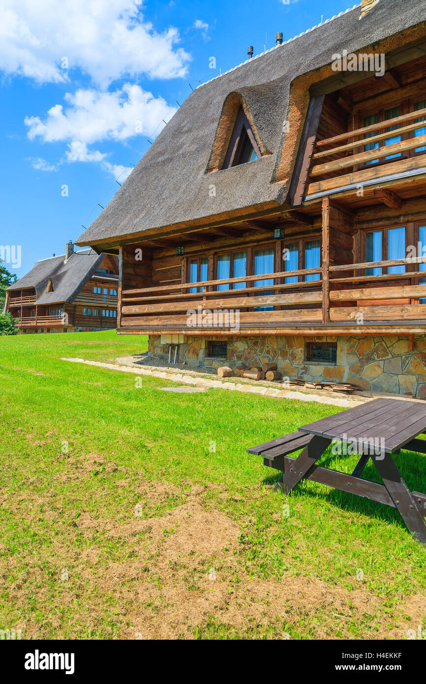 Tavolo da picnic sull'erba e le tradizionali case di montagna in un villaggio vicino a Arlamow, monti Bieszczady, Polonia Foto Stock