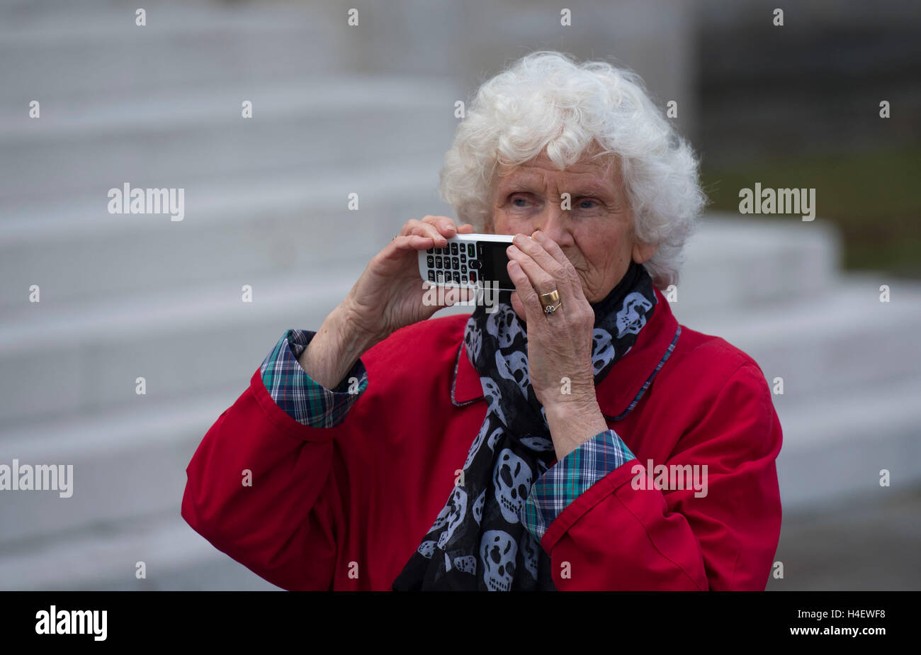 Un anziano pensionato oap utilizzando la tecnologia cellulare per scattare una foto. Foto Stock