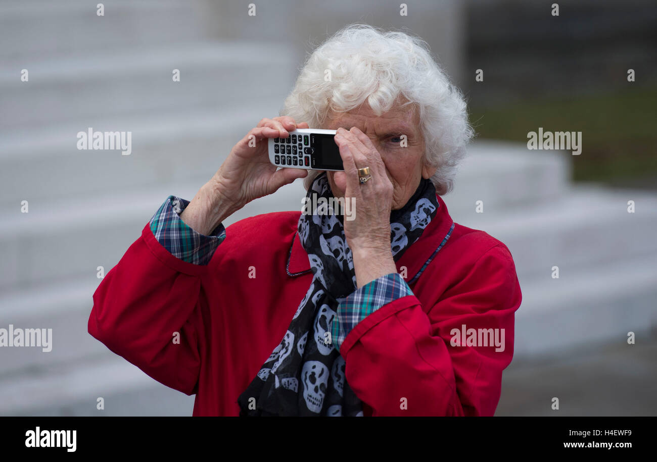 Un anziano pensionato oap utilizzando la tecnologia cellulare per scattare una foto. Foto Stock